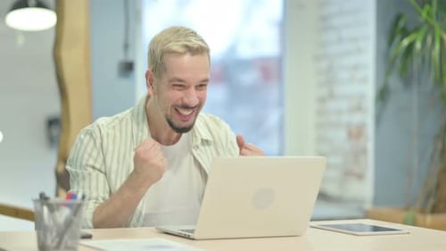 Young Man Celebrates Success at His Workplace