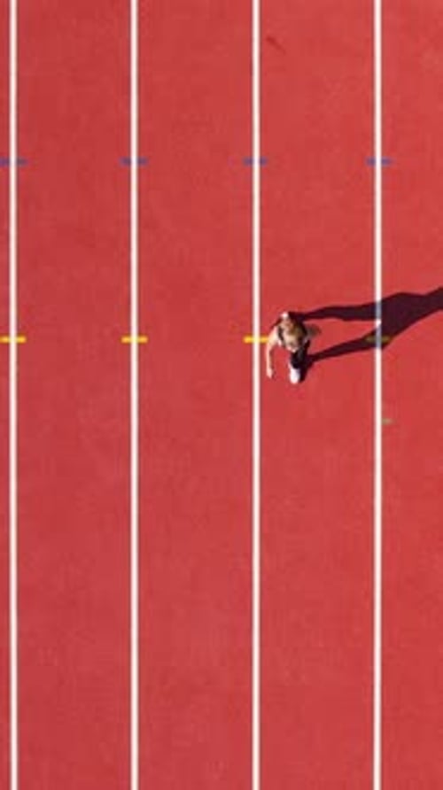 Vertical Aerial Top Down View Of Woman Running On Red Running Track