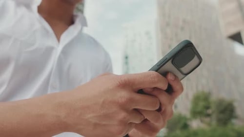 Close-up of young businessman's hands typing on smartphone