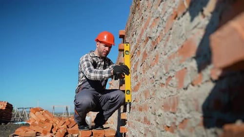 Der Baumeister überprüft die Wandausrichtung mit dem Nivellierwerkzeug