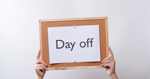 Woman's hand shows the paper on board with the word Day off in white studio background with copy spa