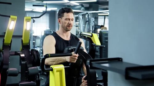 Muscular Man Training on Row Machine in Modern Gym Weigh Lifting Exercise