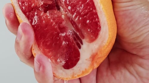 Squeezing Grapefruit in Hand, Releasing Juice