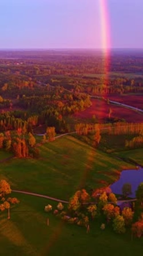 Golden Sunset Over Farmland and Rainbow Across Countryside