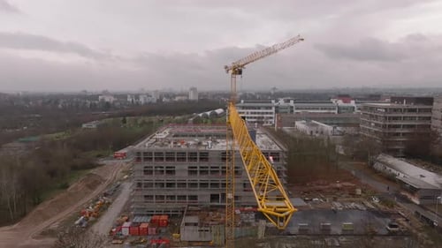 Fly Along Long Arm of High Tower Crane on Construction Site in Suburbs Modern Multistorey Building