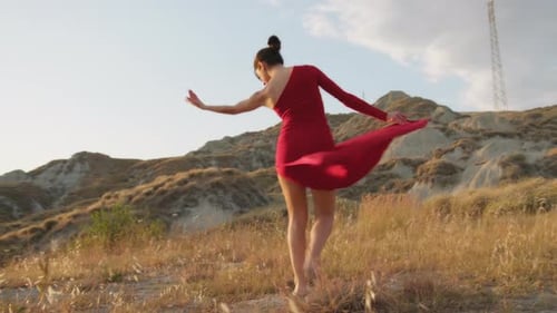 Woman Dances in a Red Dress on Grassy Hill