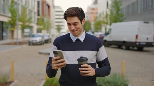 Handsome Businessman Using Mobile Phone While Walking on a Street in Downtown