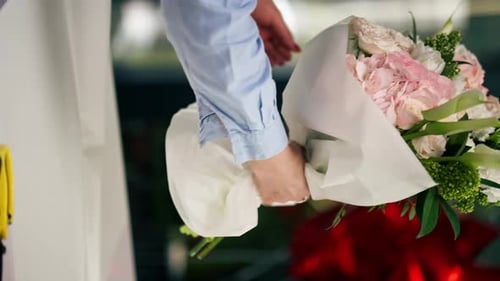 Close Up in a Flower Shop Florist Wraps a Readymade Delicate Bouquet in a White Paper Wrapper