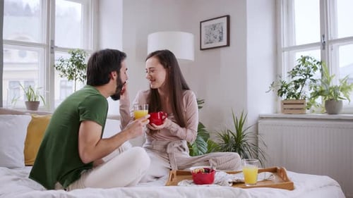 Couple Enjoying Breakfast in Bed with Juice and Fruit