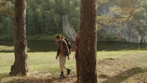 Two Hikers with Backpacks Walking through Pine Forest