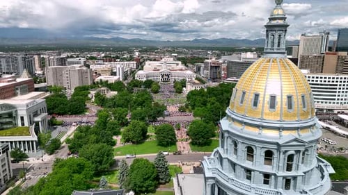 Pase aéreo por la cúpula dorada del Capitolio del Estado de Colorado hacia el Parque del Centro Cívico, una reunión de multitudes para