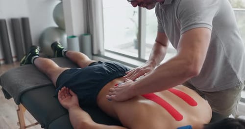 Man Receiving Kinesiology Tape for Back Pain