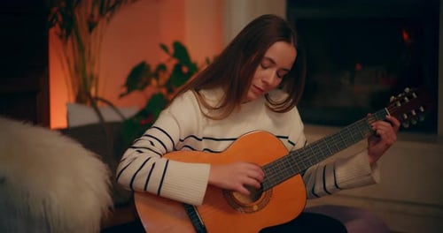 Young Woman Plays Guitar in Cozy Setting