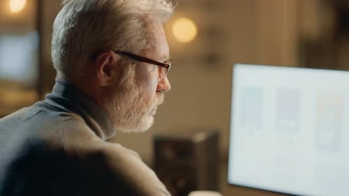 Creative Middle Aged Mobile Software Designer Sitting at His Desk Uses Desktop Computer