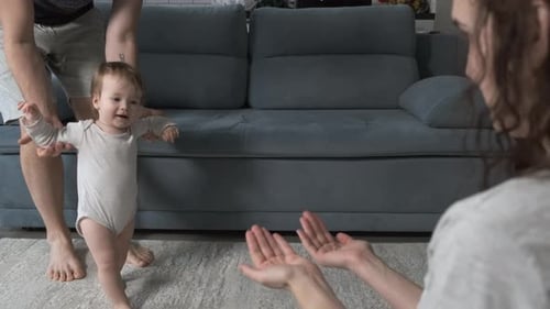 Close Up of Parents Encouraging Smiling Baby Girl to Take First Steps and Walk at Home Shot in Slow