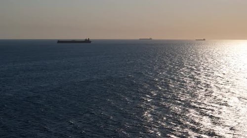 Caminhões aéreos operam enquanto navios porta-contêineres esperam no meio do oceano na costa