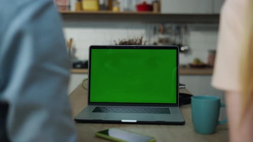 Unknown Young Couple Watching Greenscreen Laptop Sitting At Kitchen Table With Coffee Close Up. B...