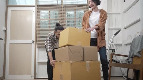 Couple Stacking Cardboard Boxes Indoors, Moving Day