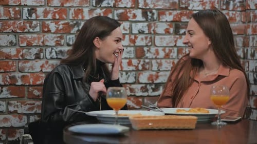 De jeunes filles joyeuses bavardent et chuchotent entre elles alors qu'elles sont assises dans un café