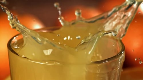 Ice Cube Dropping in Glass of Orange Juice