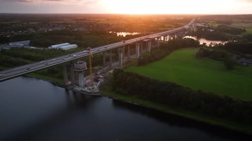 Aerial shot of elevated highway bridge under construction across Kiel Canal at sunset with support p