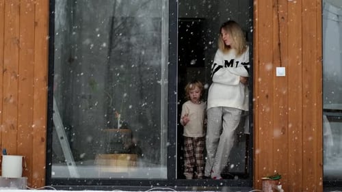mother and son standing at open door to terrace in snowy weather
