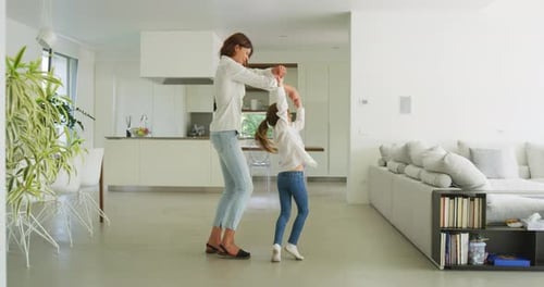 Authentic shot of happy smiling mother and daughter are having fun to dance together just moved in
