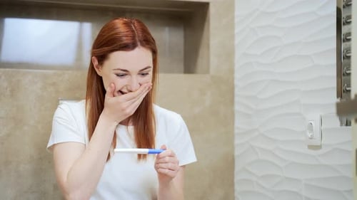 Happy caucasian young woman rejoices in positive pregnancy kit test for motherhood. Close up