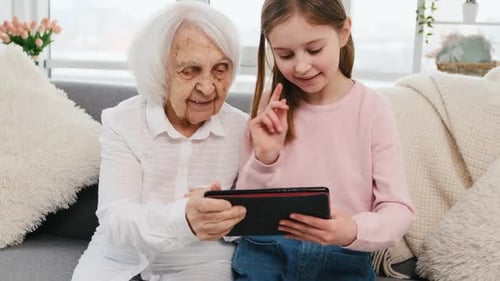 Girl and Senior Woman Using Tablet Together at Home