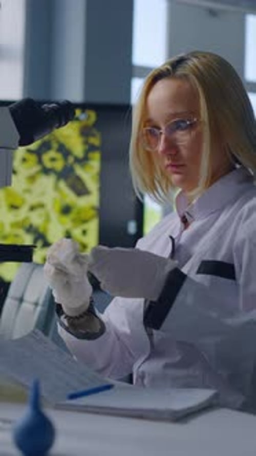 Female Scientist Analyzing Sample Using Microscope in Laboratory