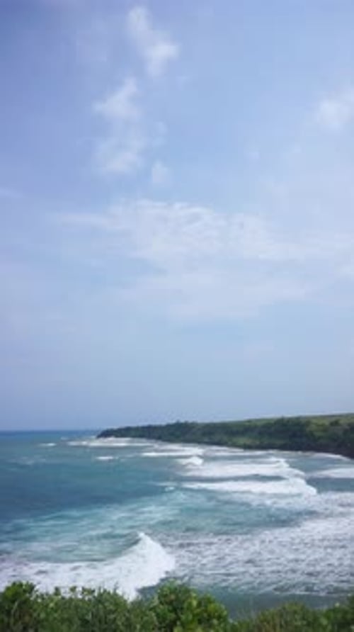 hermoso video vertical: tramo de playa con agua de mar azul con grandes olas durante el día