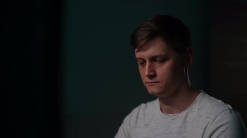 Young Man Looking at Screen in Dark Room