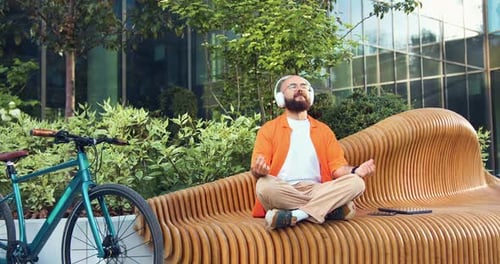 Bearded Man Meditating on Bench in Urban Park
