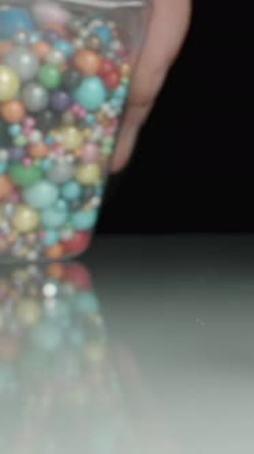 Vertical video. I Drop a Jar with Multicolored Sugar Sprinkles for Decorating Pastries.