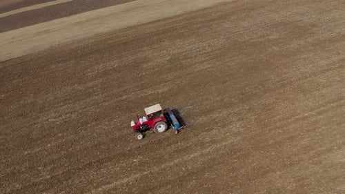 Slow motion aerial view of tractor, combine harvester plowing agricultural land
