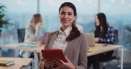 Businesswoman Smiling Holding a Tablet in an Office