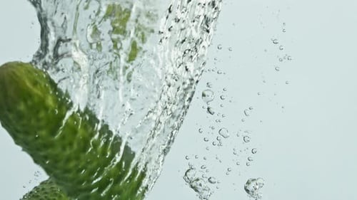 Cucumbers falling into water with bubbles in slow motion