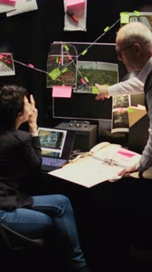 Detectives Working Together in Dark Office at Desk