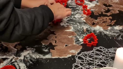 Up close cutting gingerbread cookie dough into shapes for Christmas celebration