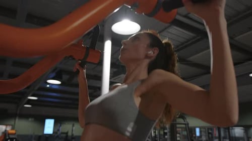 Fitness-Frau pumpt Muskeln auf und macht Klimmzugübungen im Fitnessstudio