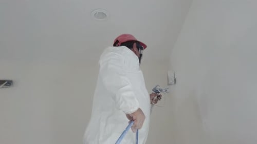 Adult Painting White Wall with Paint Sprayer