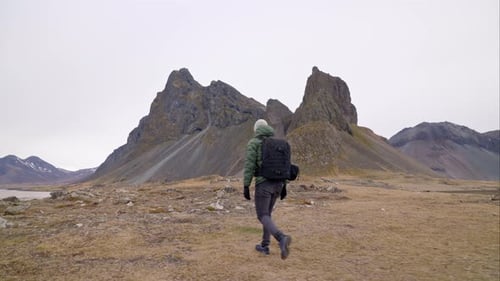 Hiker Walking Towards Majestic Mountain Range