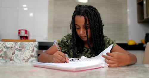 Young Girl Studying and Writing in Notebook Indoors