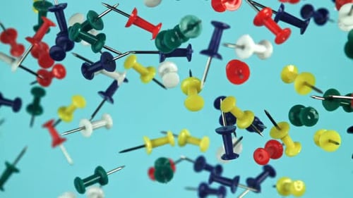 Colorful Thumbtacks Floating on Light Blue Background
