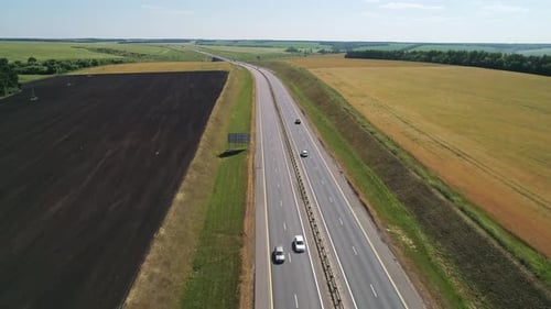 Aerial View of a Cars Driving Through Highway Road Among Agriculture Fields and Green Countryside