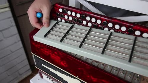 Man Repairing a Red Button Accordion Close Up