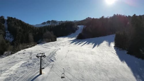 A Drone Flies Over a Ski Slope Where Skiers are Skiing on a Sunny Winter Day