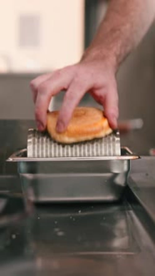 Adult Grating Buns in a Workplace Kitchen