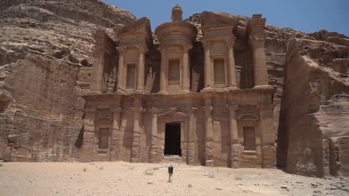 Lonely Man in Front of Monastery Carved in Sandstone Cliff. Petra Archaeological Site, Jordan. Wide