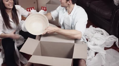 Happy couple unpacking boxes in new home